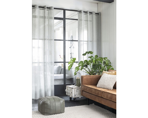 Wohnzimmer mit Sofa, Zimmerpflanze, Teppich, Pouf und Vorhängen