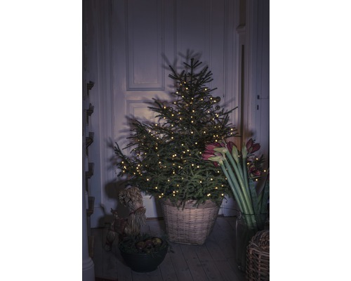 Dekorierter Weihnachtsbaum im geflochtenen Korb mit Amaryllis und Strohfigur
