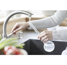 Eine Person füllt einen Eisballbereiter unter einem Wasserhahn.