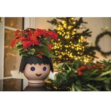 Blumentopf in Form einer Playmobil-Figur mit Weihnachtsstern und Weihnachtsbaum im Hintergrund
