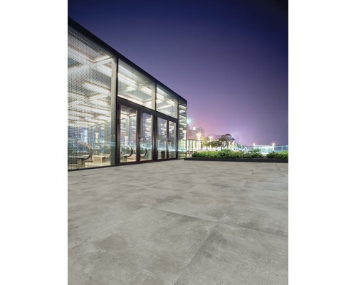 Verlegung von Bodenfliesen im Außenbereich vor einem modernen Gebäude bei Nacht.