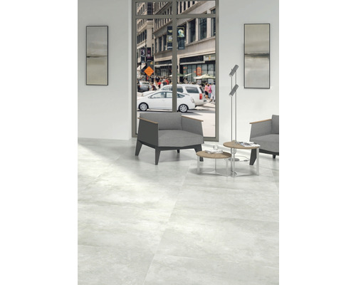 Heller Raum mit Bodenfliesen, Sessel und Ausblick auf eine belebte Stadtstraße.