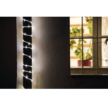 Dekorative Lichterkette um einen Pfosten gewickelt, Zimmerpflanze im Fenster sichtbar.