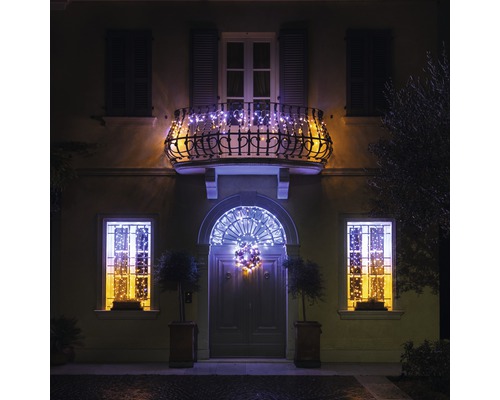 Hausfassade mit weihnachtlicher Beleuchtung an Balkon, Fenstern und Tür