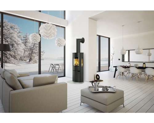Heller Wohnraum mit Kaminofen, Sofa, Esstisch und Blick auf eine verschneite Landschaft
