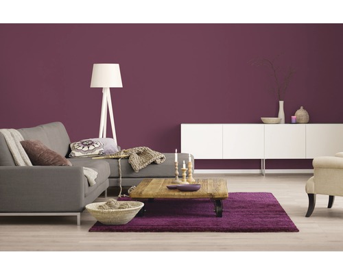 Wohnzimmer mit Sofa, Couchtisch, Teppich und weißer Kommode vor einer farbigen Wand