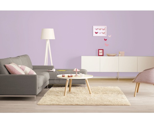 Heller Wohnraum mit Sofa, Teppich, Tisch und Lampe vor einer farbigen Wand