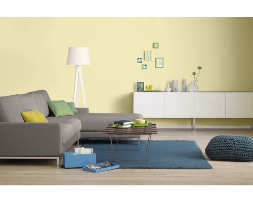 Wohnzimmer mit grauer Couch, Couchtisch und weißem Sideboard vor gelber Wand