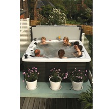 Personen entspannen sich in einem Whirlpool mit Abdeckung auf einer Terrasse