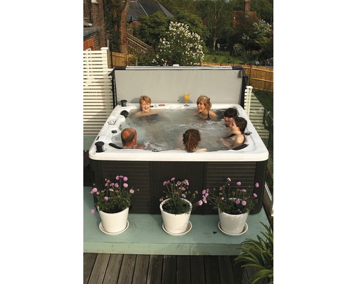 Personen entspannen sich in einem Whirlpool mit Abdeckung auf einer Terrasse