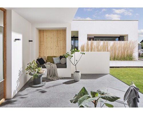 Helle Terrasse mit Sitzbereich, Holzwand, Pflanzen und Gartenblick