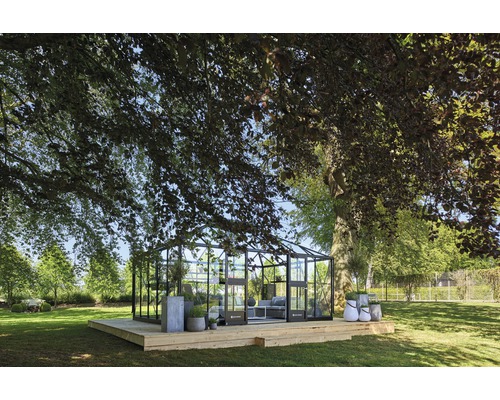 Gewächshaus auf einer Holzterrasse im Garten