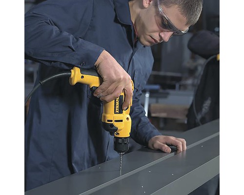 Mann bohrt mit einer gelben Bohrmaschine Löcher in ein Metallprofil.