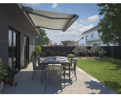 Terrasse mit Markise, Gartentisch und Stühlen vor einem Haus.