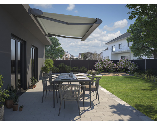 Terrasse mit Markise, Tisch und Stühlen vor einem Haus mit Garten