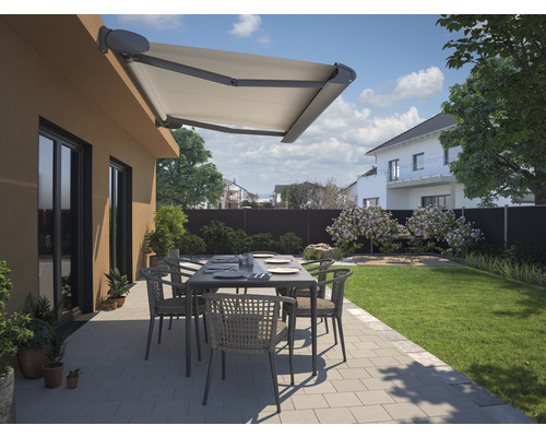 Terrasse mit Markise, Tisch und Stühlen in einem Garten.