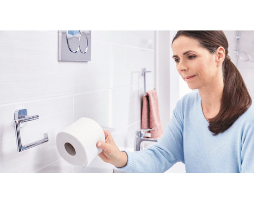 Frau im Badezimmer mit Toilettenpapier und Toilettenpapierhalter