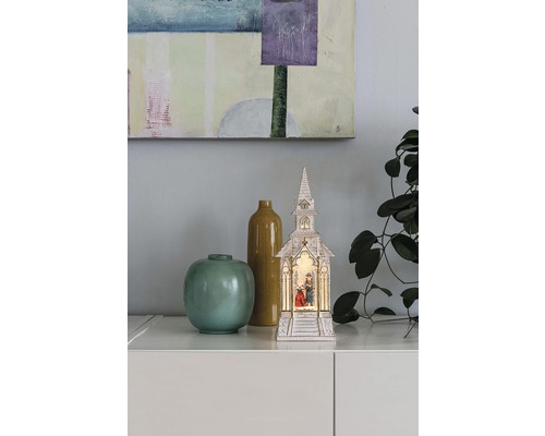 Dekorative beleuchtete Kirche mit Krippe und zwei Vasen als festliche Dekoration