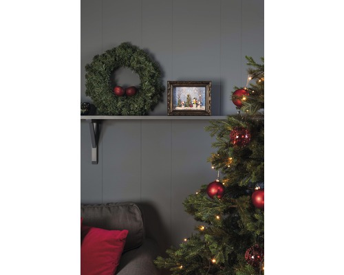 Festlich geschmücktes Wohnzimmer mit Weihnachtsbaum, Kranz und Dekorationen auf einem Regal