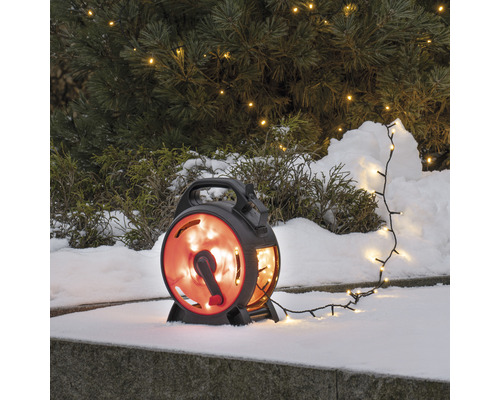 Lichterkette mit Aufroller im Schnee vor einem Baum