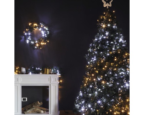 Weihnachtliche Dekoration mit beleuchtetem Baum, Kranz und Kaminsims