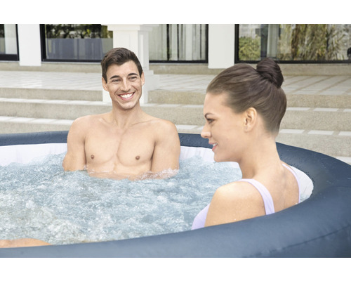 Zwei Personen entspannen in einem aufblasbaren Whirlpool im Freien.