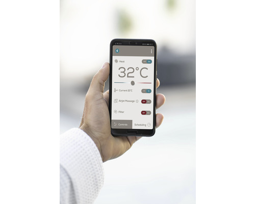 Ein Smartphone mit einer App zur Steuerung von Heizung, Massage und Filterfunktionen wird in der Hand gehalten.