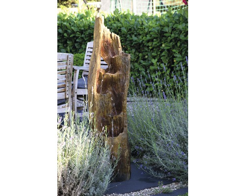 Gartenszene mit Baumstammbrunnen, Gartenmöbeln und Lavendel