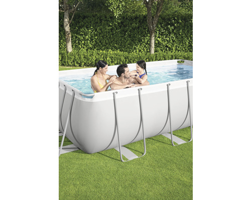 Familie entspannt im rechteckigen Aufstellpool im Garten.