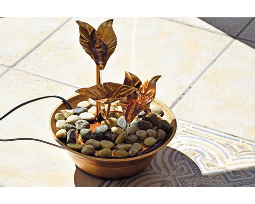 Zimmerbrunnen mit Steinen und kupferfarbenen Blättern in einer Schale