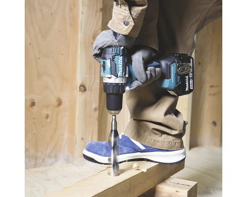 Eine Person bohrt mit einer Akku-Bohrmaschine von Makita ein Loch in ein Holzbrett.
