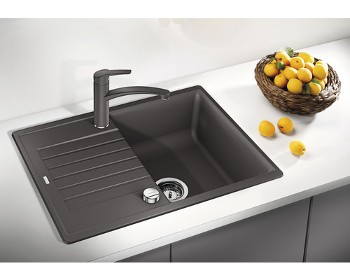 Dunkelgraue Spüle mit Abtropffläche und Armatur auf einer Küchentheke mit Zitronen in einem Korb