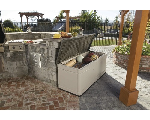 Geöffnete Aufbewahrungsbox im Außenbereich neben einer Außenküche auf einer Terrasse mit Sportgeräten darin