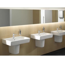 Drei weiße Waschbecken mit Armaturen und Seifenspendern in einem Badezimmer.