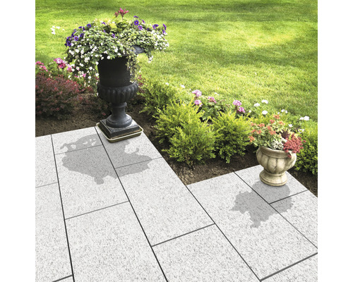 Gartenweg mit hellen Pflastersteinen und bepflanzten Blumenkübeln