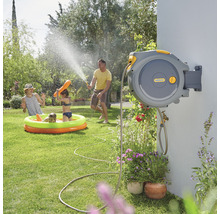 Familie nutzt eine automatische Gartenschlauchbox von Hozelock zum Bewässern und Spielen im Garten.