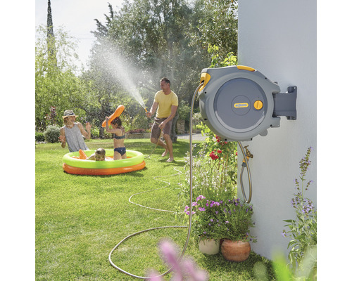 Familie nutzt eine automatische Gartenschlauchbox von Hozelock zum Bewässern und Spielen im Garten.