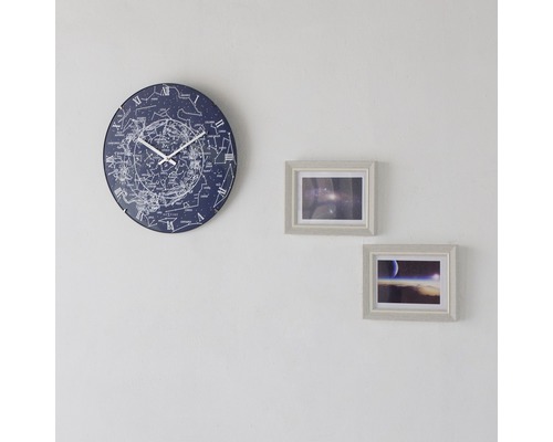 Wanduhr mit Sternbildern und zwei gerahmten Bildern an einer Wand