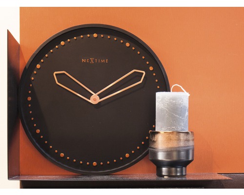 Dekorative Szene mit einer Uhr der Marke Nextime und einer Kerze in einem Kerzenständer