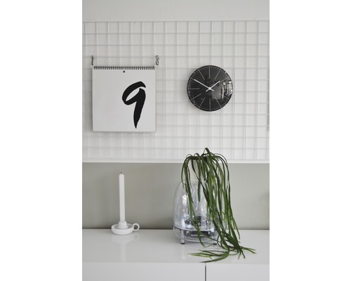 Dekoratives Zimmerambiente mit Kalender, Uhr und Zimmerpflanze auf einem Schrank