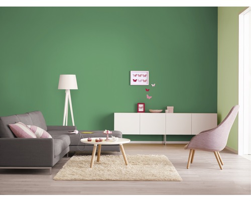 Wohnzimmer mit Sofa, Sessel, Teppich und grüner Wand