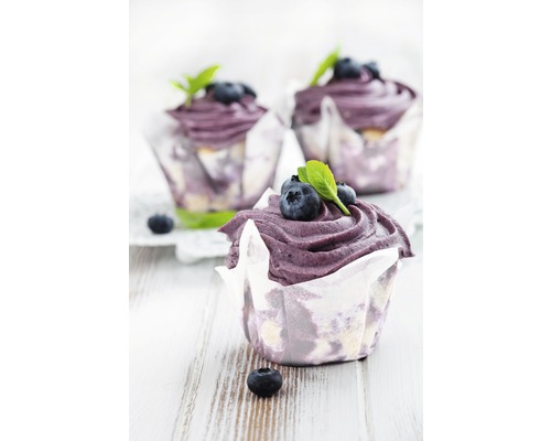 Drei Blaubeer-Muffins mit blauem Zuckerguss und frischen Blaubeeren in Papierförmchen