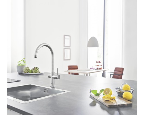 Küchenspüle mit Armatur auf einer Arbeitsfläche mit Zitronen und Kräutern.