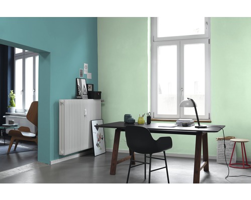 Büro mit Schreibtisch, Stuhl, Heizkörper und farbigen Wänden.