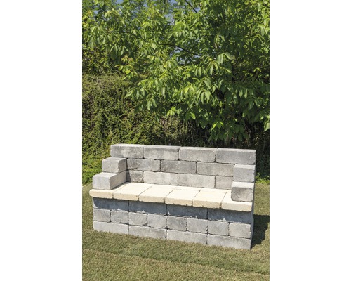 Gartenbank aus Betonsteinen vor grünem Hintergrund