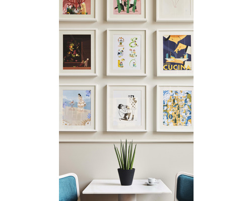 Wand mit gerahmten Bildern über Tisch und Topfpflanze