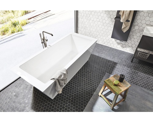 Badezimmer mit rechteckiger Badewanne, Armatur und sechseckigen Bodenfliesen.