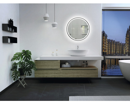 Modernes Badezimmer mit Waschtisch, rundem Spiegel mit Beleuchtung, Regalen und Zimmerpflanze