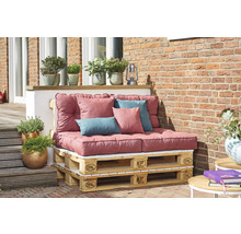 Gartenlounge aus Europaletten mit Polsterauflagen und Kissen vor einer Ziegelwand