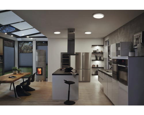 Helle, moderne Wohnküche mit Kochinsel, Essbereich, Kamin und Deckenleuchten